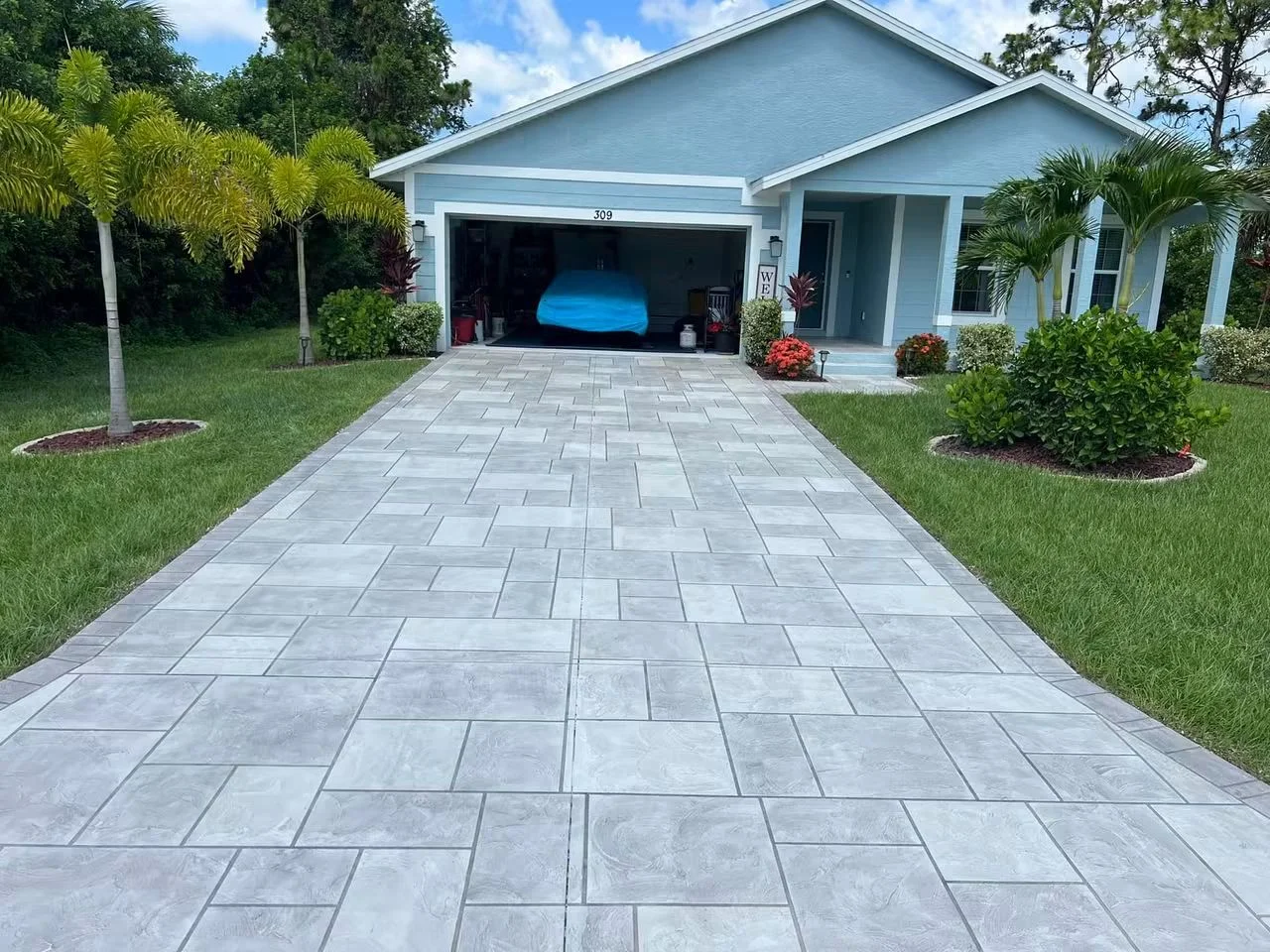 Light gray stamped concrete driveway with geometric pattern leading to garage
