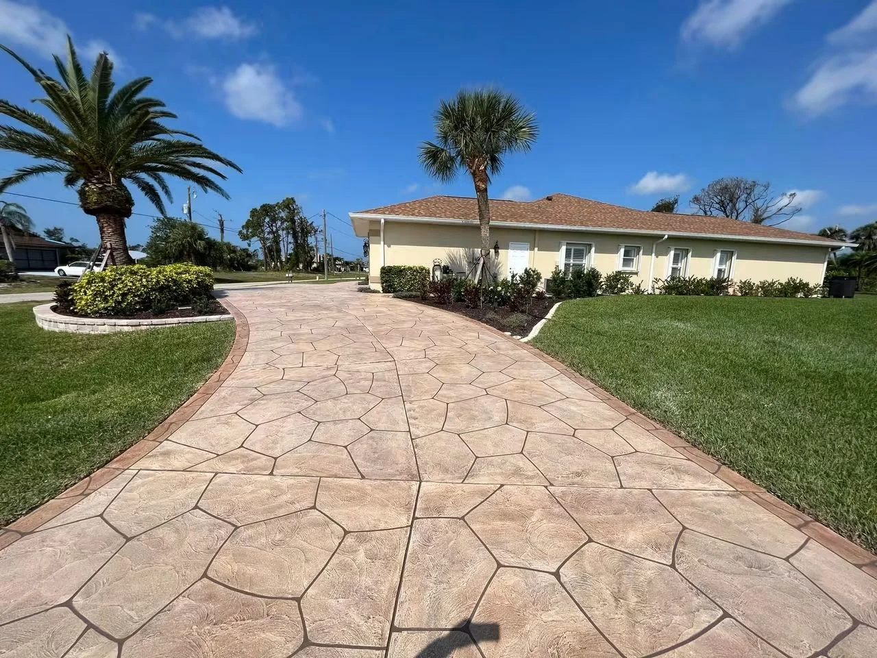 Stamped concrete driveway with stone pattern, curved layout, and red border edging