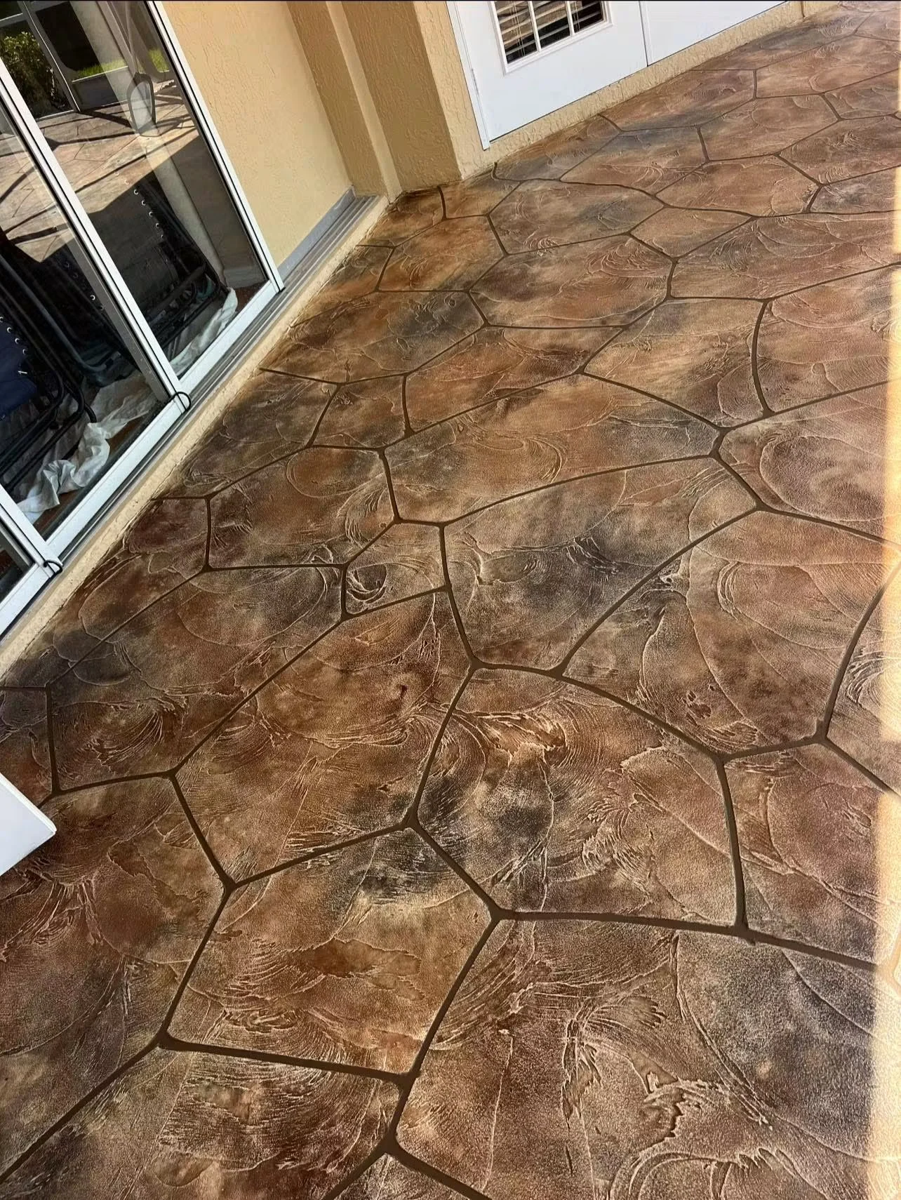 Stamped concrete patio with ashlar slate pattern and brown wood-grain texture finish
