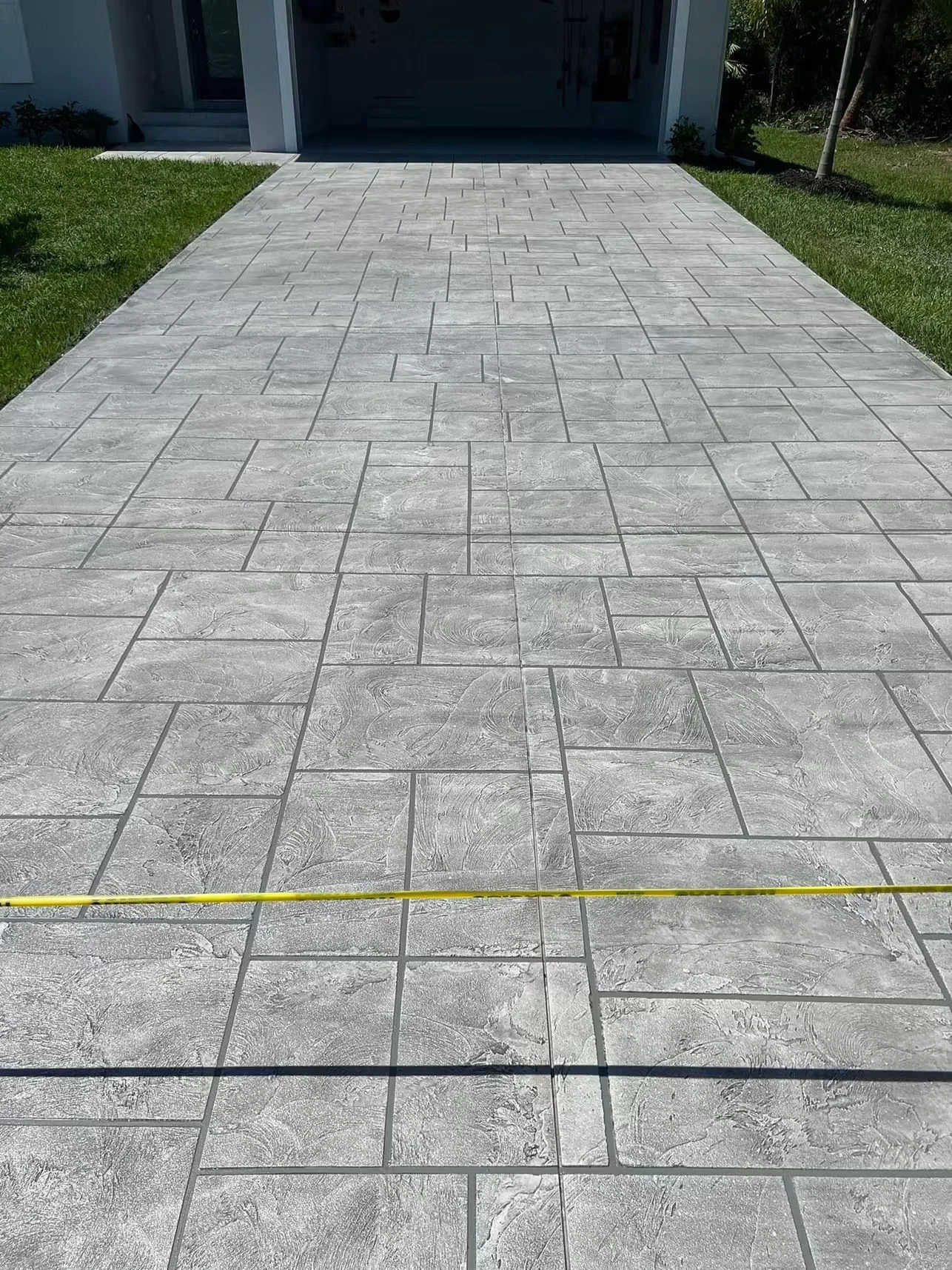 Gray stamped concrete patio with herringbone pattern and wood-grain texture finish