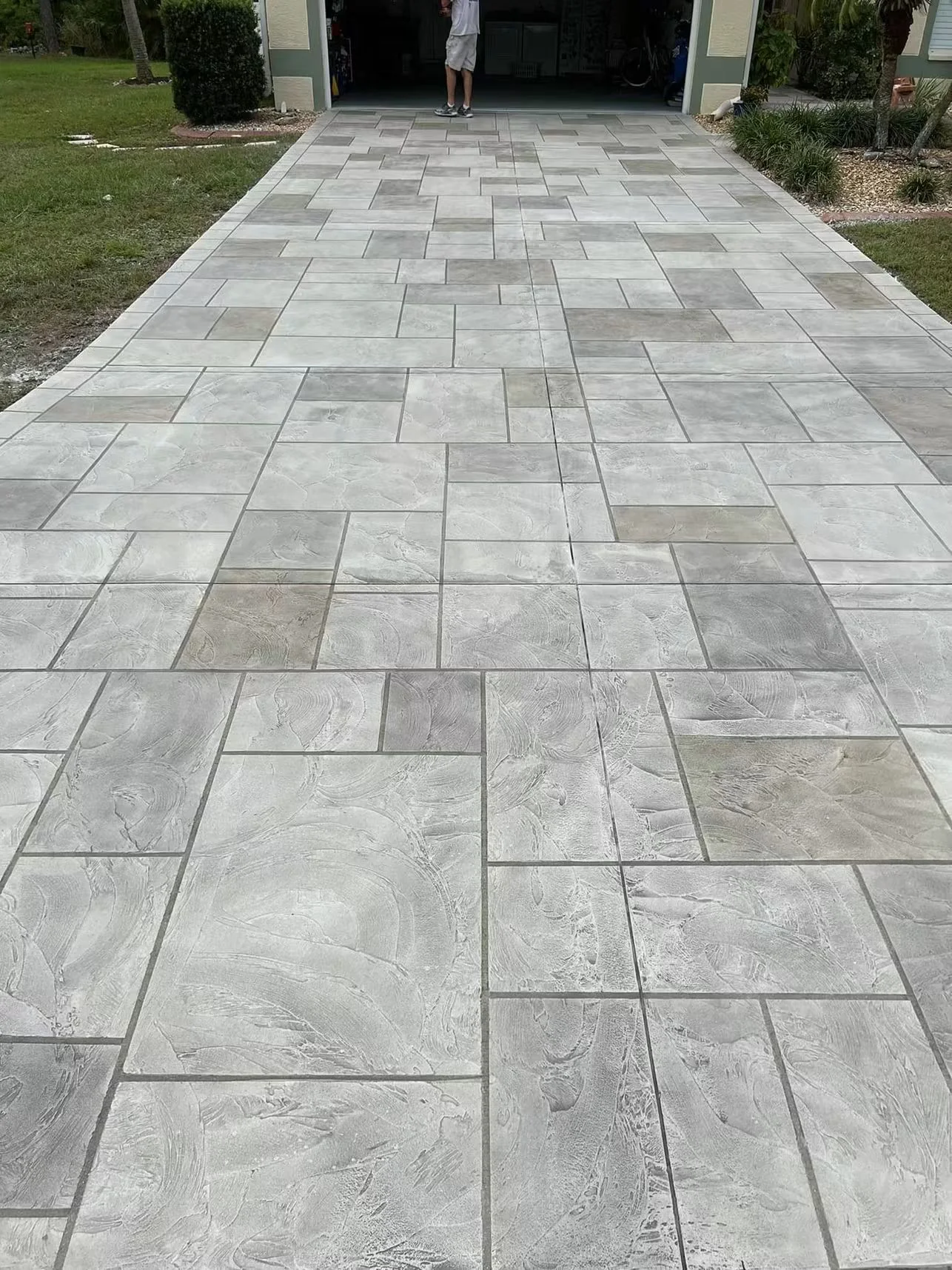 Gray textured concrete driveway with mixed rectangular pavers in herringbone-style pattern