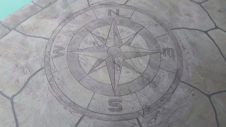 Compass rose medallion scored into concrete with cardinal directions and eight-point star design