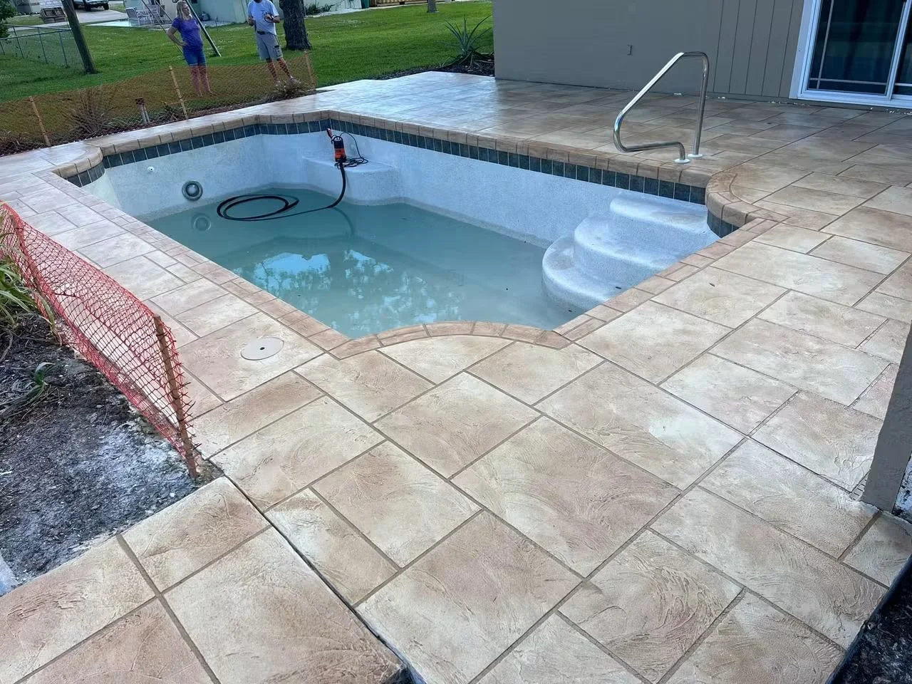 Diagonal concrete pavers around pool deck with tumbled edges and decorative tile border