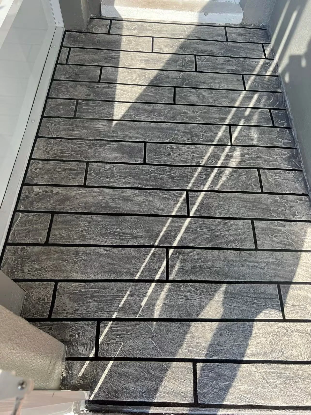 Charcoal and light wood-grain textured concrete floor with black grout lines in running bond pattern